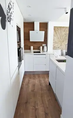a kitchen with white cabinets and a wooden floor at Design Apartment with Sea View in Castelldefels