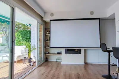 a large screen in a living room with a table at Design Apartment with Sea View in Castelldefels