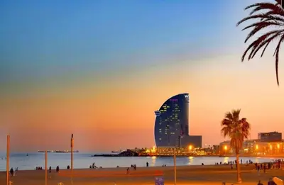 a building on the beach at sunset with people on the beach at Gran apartamento ideal grupos muy cerca Barcelona in Badalona