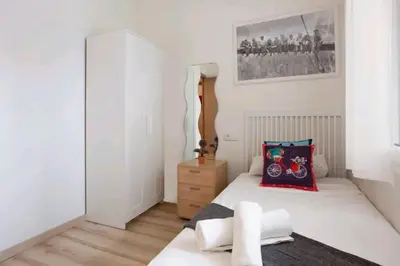 a white bedroom with a bed and a dresser at Centric Apartment Gran Via 5 in Hospitalet de Llobregat