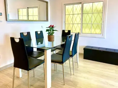 a dining room with a glass table and blue chairs at BEACHFRONT APARTMENT Castelldefels in Castelldefels