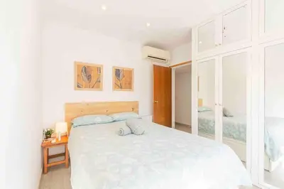 a white bedroom with a large bed and a table at BEACHFRONT APARTMENT Castelldefels in Castelldefels