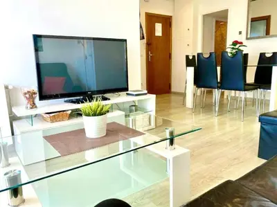 a living room with a tv on a glass table at BEACHFRONT APARTMENT Castelldefels in Castelldefels