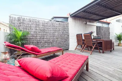 a patio with red pillows and a table and chairs at My Space Emirates - Park Güell Triplex with Private Terrace in Barcelona
