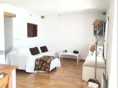 a white bedroom with a bed and a table at Apartment Raco in Vilanova i la Geltrú