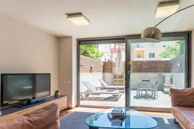 a living room with a television and a glass table at My Space Emirates - Splendid Apartment with Terrace and Pool near Park Güell in Barcelona