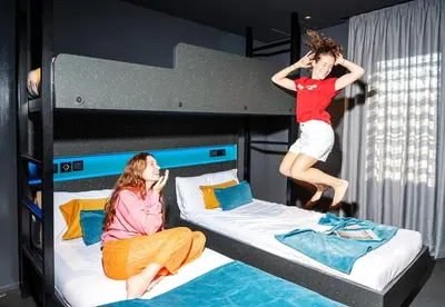 two girls jumping on bunk beds in a room at AMISTAT City Hostel Barcelona in Barcelona