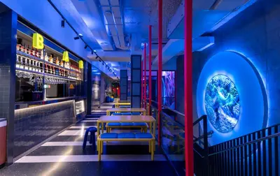 a row of tables and chairs in a room with blue lights at AMISTAT City Hostel Barcelona in Barcelona