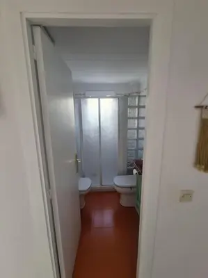 a white bathroom with a toilet and a window at Nice beachside 2-BD apt near Barcelona in Cunit
