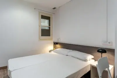 a white bed in a room with a desk and a window at AB Margarit Apartments in Barcelona
