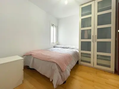 a white bedroom with a bed and a window at Apartment Picasso in Vilanova i la Geltrú