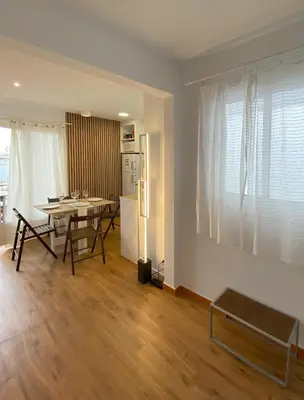 a kitchen and dining room with a table and refrigerator at Ático con terraza! Ideal para vivir Sitges todo el año in Sitges