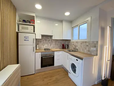 a kitchen with a white refrigerator and a washer and dryer at Ático con terraza! Ideal para vivir Sitges todo el año in Sitges