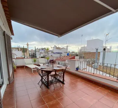 a patio with a table and chairs on a balcony at Ático con terraza! Ideal para vivir Sitges todo el año in Sitges