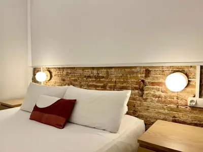 a bed with two lights on a brick wall at Stay U-nique Apartments Vila de Gracia II in Barcelona