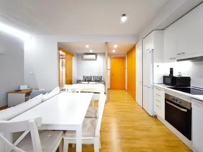 a kitchen and living room with a white table at Moderno apartamento tipo loft en Terrassa centro in Terrassa