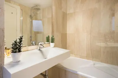 a bathroom with a sink and a mirror and a tub at My Space Emirates - Modern Duplex with Private Garden and Swimming Pool in Barcelona
