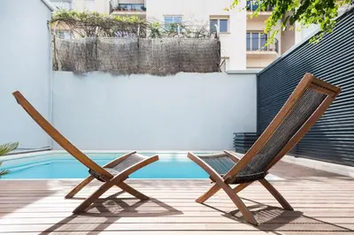 two chairs sitting on a patio with a pool at My Space Emirates - Modern Duplex with Private Garden and Swimming Pool in Barcelona