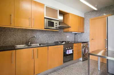 a kitchen with wooden cabinets and a sink and a microwave at My Space Emirates - Spacious Apartments near the City Center in Barcelona