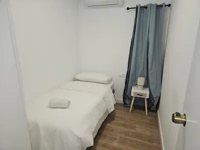a small bedroom with a white bed and a table at Vilamarlux VIII in Vilassar de Mar