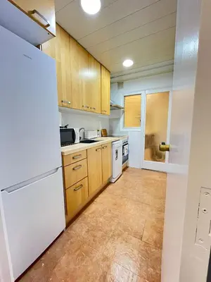 a kitchen with wooden cabinets and a white refrigerator at Vilamarlux VIII in Vilassar de Mar