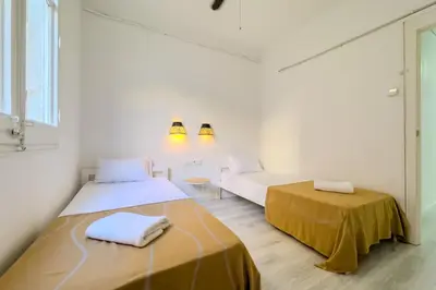 a white room with two beds and a couch at Bed&BCN Mas Apartments in Hospitalet de Llobregat