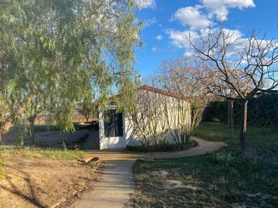 a small white house with a tree and a sidewalk at La Geneta Casa Vacacional in Vilobi Del Penedes