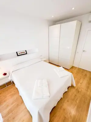 a bedroom with a white bed and a wooden floor at Anna & Thomas - Sitges Center Apt in Sitges
