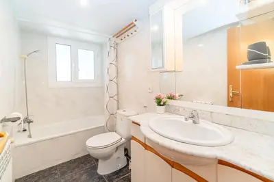 a white bathroom with a toilet and a sink at Horizonte Azul Sitges in Sitges