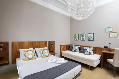 a bedroom with two beds and a chandelier at Jardinets Guest House in Barcelona