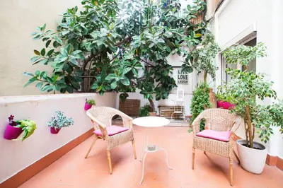 a patio with a table and chairs and trees at Jardinets Guest House in Barcelona