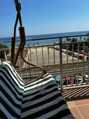 a bench sitting on a balcony overlooking the beach at Apartamento a primera línea de Mar in Pineda de Mar