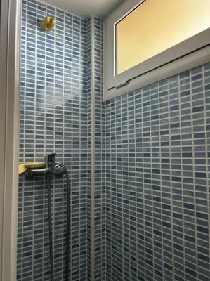 a bathroom with a shower with blue tiles on the wall at Apartamento a primera línea de Mar in Pineda de Mar