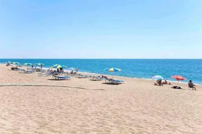 a group of people sitting on a beach with umbrellas at Apartamento a primera línea de Mar in Pineda de Mar