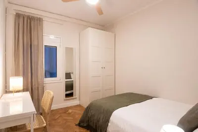 a bedroom with a bed and a desk and a window at Warmth and comfort in the sought-after Eixample in Barcelona