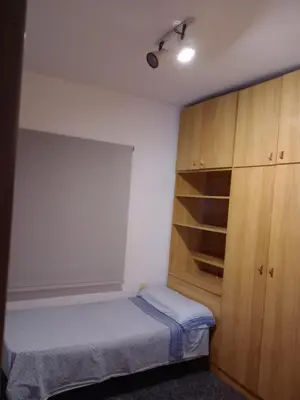 a small bedroom with a bed and a wooden cabinet at Casa en Barcelona in Papiol