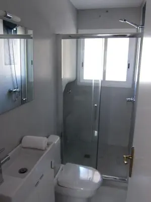 a white bathroom with a shower and a toilet at Preciosa casa en el centro con terraza y patio in Sitges
