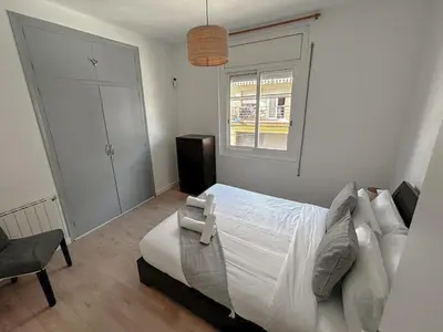 a bedroom with a bed and a chair and a window at Sitges Best Holidays Apartment in Sitges