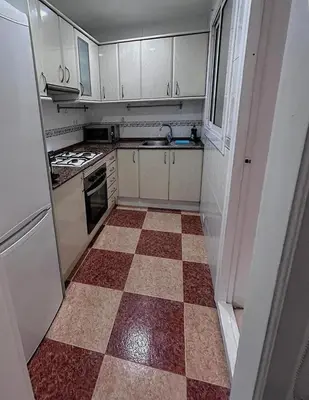 a kitchen with a checkered floor and white cabinets at Sitges Best Holidays Apartment in Sitges