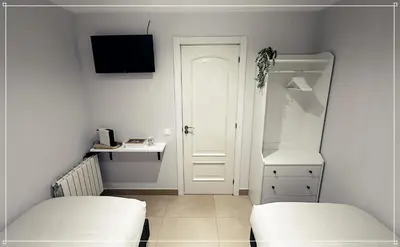 a white room with two beds and a door at FIRA GRAN VIA II in Hospitalet de Llobregat