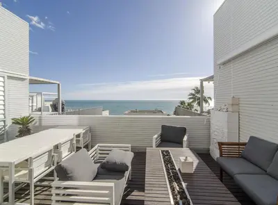 a patio with a table and chairs and the ocean at Duplex vistas mar con piscina in Sant Pere de Ribes