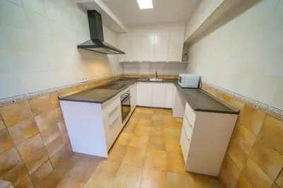 a large kitchen with white cabinets and a sink at HomeHolidaysRentals Anais - Costa Barcelona in Pineda de Mar