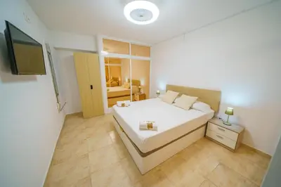 a bedroom with a white bed and a television at HomeHolidaysRentals Anais - Costa Barcelona in Pineda de Mar