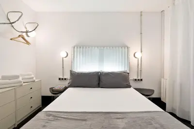 a white bedroom with a large bed and a window at Eulalias Lodges Barcelona in Barcelona