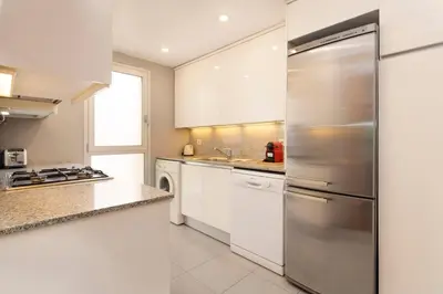 a kitchen with white cabinets and a stainless steel refrigerator at Enjoy Apartments Calle Paris Super Stylish in Barcelona