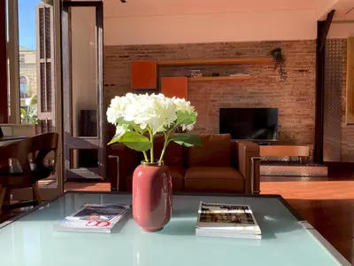 a red vase with white flowers on a table at Luminous Designer Loft Style Apt Eixample Views By MyRentalHost in Barcelona