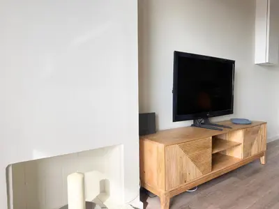 a flat screen tv sitting on top of a wooden entertainment center at Atico Isabel in Castelldefels