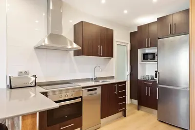 a kitchen with wooden cabinets and a stainless steel refrigerator at El balcón de Sagrada Familia in Barcelona