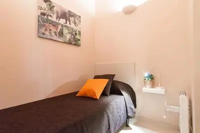 a bedroom with a bed with an orange pillow on it at Family apartment Plaza España 2 in Barcelona