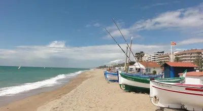 a beach with boats sitting on the sand at The White Lilies in Pineda de Mar